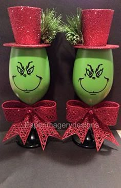 two green vases with red bows and hats on them, one has a grin face painted on it