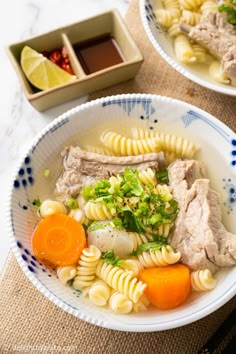 two bowls filled with pasta, meat and veggies on top of a table