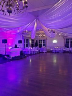 an empty dance floor is lit up with purple lights and draping over it