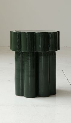 four green vases stacked on top of each other in the middle of a room