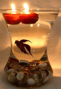 a glass vase filled with rocks and two lit candles