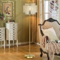 a living room with a chair and a lamp on the floor in front of a window