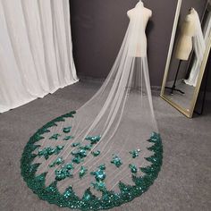 a wedding veil with green sequins on it and a mannequin in the background