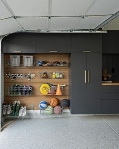 an organized garage with gray cabinets and baskets on the wall, along with other items