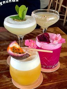 three different types of cocktails sitting on top of a wooden table next to each other