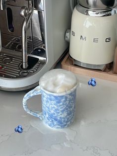 a blue and white coffee mug sitting next to an espresso machine