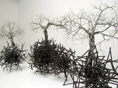 three sculptures made out of sticks and branches in the shape of trees on a snow covered ground