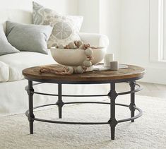 a living room with a couch, coffee table and pillows on the floor in front of it