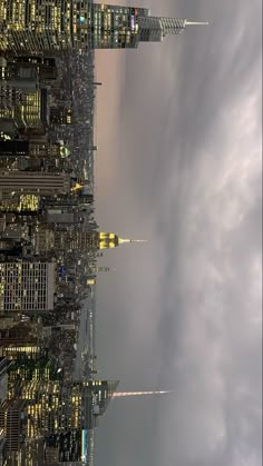 the skyline of new york city at night with skyscrapers lit up and clouds in the sky