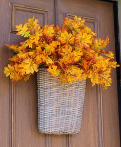 a basket filled with yellow and red leaves on top of a wooden door sill