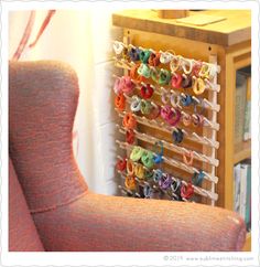 an orange chair next to a book shelf filled with books and colorful rings on it