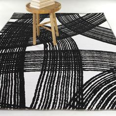 a black and white area rug with an abstract design on the floor, next to a stool