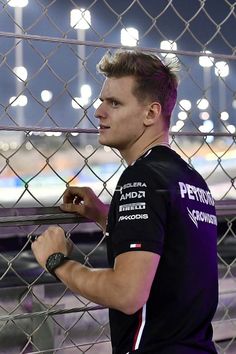 a man standing next to a fence in front of an arena