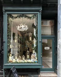 a store front with christmas decorations in the window and on the street corner, there is a birdcage that has been decorated