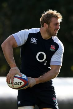 a man holding a rugby ball in his right hand and wearing a black jersey with the number 9 on it