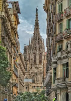 an old cathedral towering over a city filled with tall buildings and people walking down the street