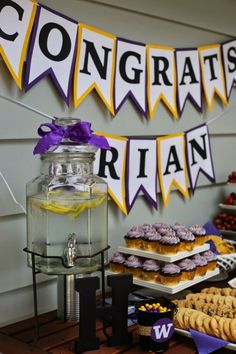 a table topped with cookies and desserts next to a sign that says congratulations rain