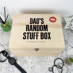 a wooden box with the words dad's random stuff in it on a marble surface