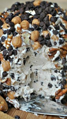 an ice cream sundae with chocolate chips and nuts on top, sitting on a wooden board