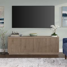 a living room with a large flat screen tv mounted on the wall above a wooden cabinet