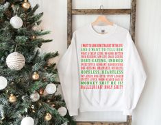 a white sweatshirt hanging on a wall next to a christmas tree with ornaments around it