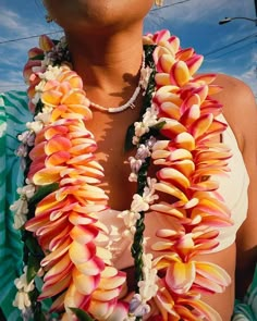 a woman wearing a necklace with flowers on it's neck and in front of a blue sky