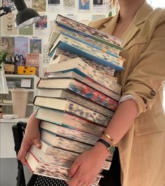 a woman holding a stack of books in her hands