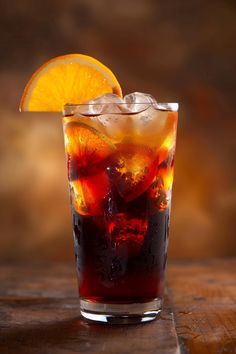 an orange slice is sitting on top of a glass filled with ice and sodas