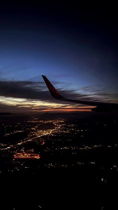 an airplane wing flying over a city at night