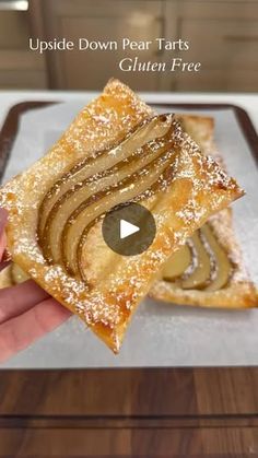 a person holding up a piece of food on top of a white plate with the words upside down pear tarts written below it