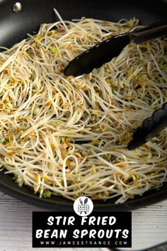 stir fried bean sprouts are being cooked in a pan with tongs on the side