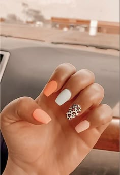 a woman's hand with an orange and white manicure holding up her fingers