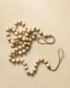 a wooden beaded cross on a white surface with a string attached to the beads