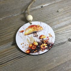 a ceramic ornament with an image of mushrooms on it hanging from a string