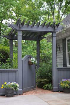 a gray house with a wooden gate and flower pots