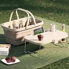 a picnic table with two coolers and some snacks on it in the grass next to each other