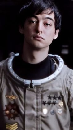 a young man wearing a space suit with patches on it's chest and collar