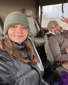 a man and woman sitting in the back seat of a car with their hands up