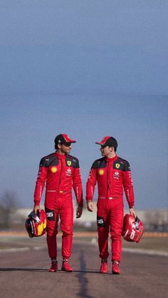 two men in red racing suits walking down the street