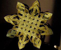 a paper snowflake is shown on a black tablecloth with gold glitters