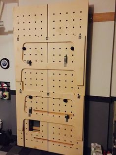 a large wooden peg board with holes on it in a garage or office area,