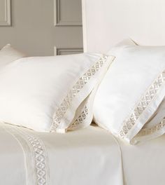 two white pillows sitting next to each other on top of a bed with white sheets