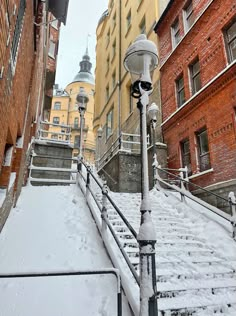 a street light covered in snow next to some brick buildings and stairs with lights on them