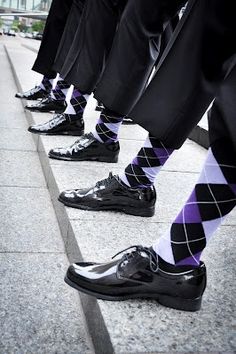 men in black and white argyle socks are lined up on the sidewalk with their legs crossed