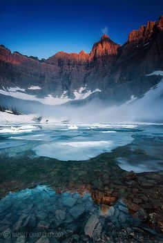 the mountains are covered in snow and ice as it sits on top of some rocks