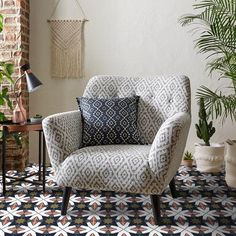 a chair sitting on top of a rug next to a potted plant