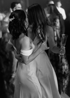 two women in white dresses hugging each other