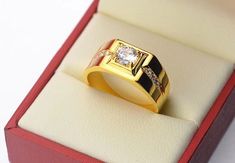 a man's gold ring in a red box with white and black diamonds on it