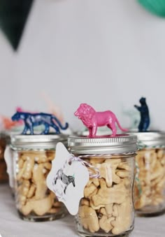 three glass jars filled with different types of nuts and animals on top of a table