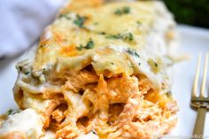 a white plate topped with lasagna covered in cheese and sauce next to a fork